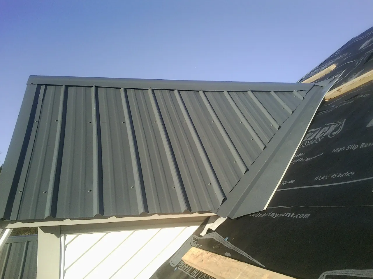 Gray metal roof panels going on over a garage gable in Pascagoula
