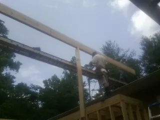 Carpenter setting a ridge beam over a new addition frame — Ice Dam Removal by Roofing Brothers in Pascagoula