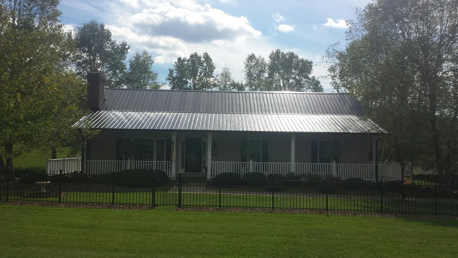 Gray metal roof on a brick ranch with a full width front porch — Gutter Guard Installation work by our crew in Pascagoula