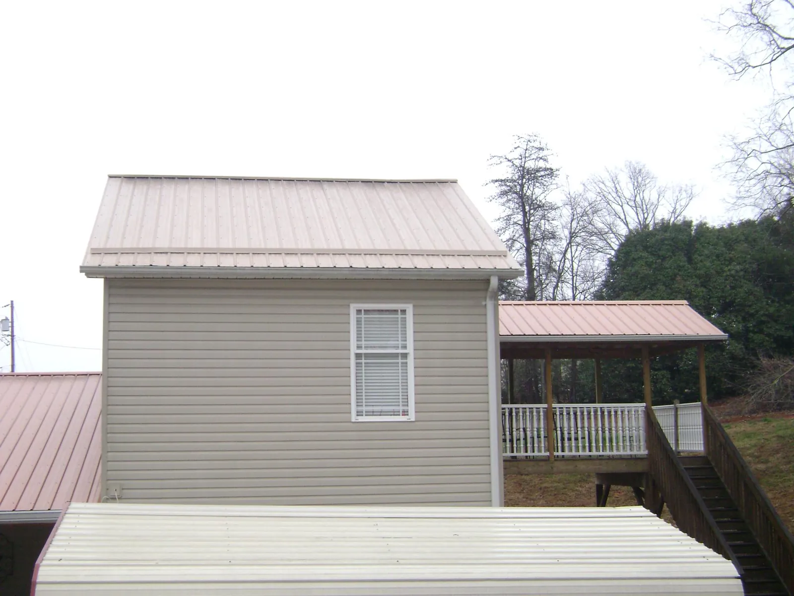 Tan metal roofs on a two story addition and attached porch, from a Roof Replacement job in Pascagoula