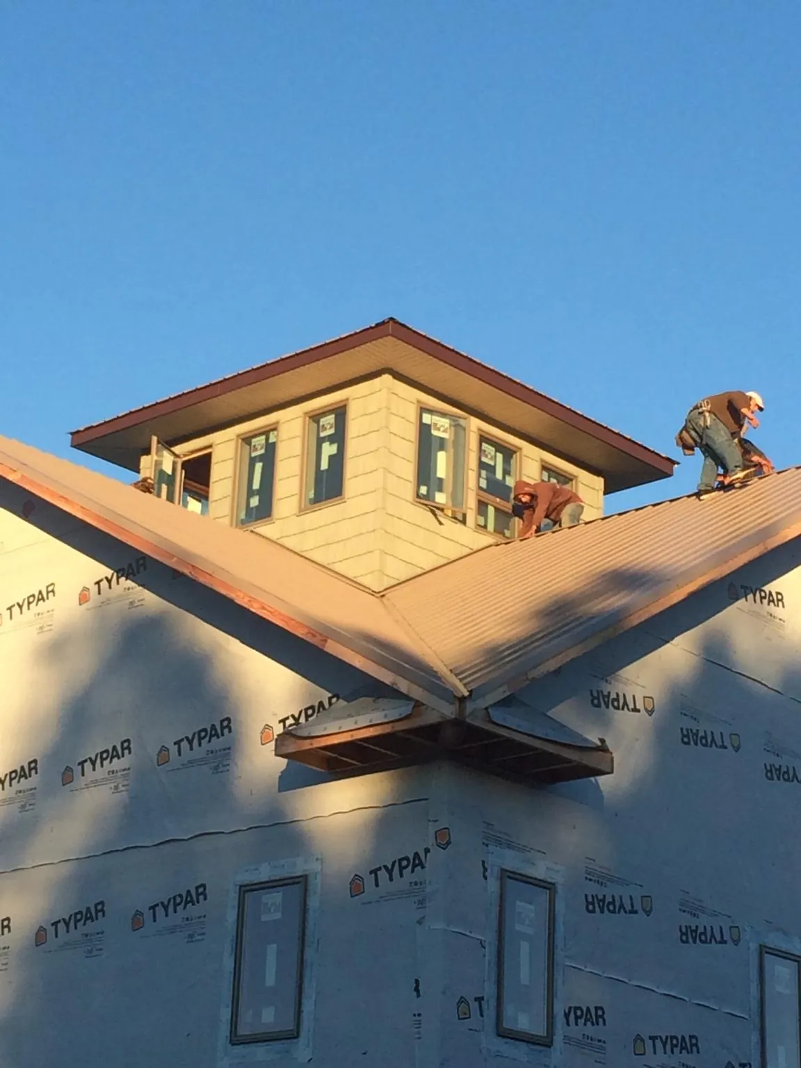 Roofers working around a rooftop cupola on a new metal roof at sunset — Roof Waterproofing in Pascagoula by Roofing Brothers